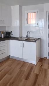 a kitchen with white cabinets and a sink at Acacias IV in Benidorm