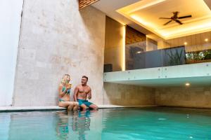 a man and a woman sitting in a swimming pool at Villa Kayu Raja in Seminyak