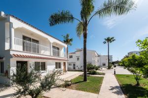 a palm tree in front of a white building at Fig Tree Z Holiday Resort in Paralimni