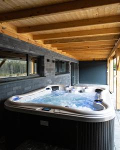 a large hot tub in a room with a wooden ceiling at Jagodówka in Soblówka