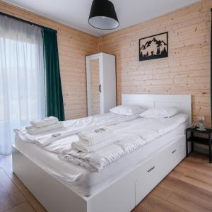 1 cama blanca grande en una habitación con paredes de madera. en Jagodówka en Sablówka