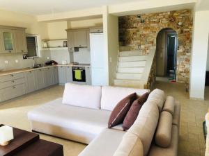 a living room with a white couch and a kitchen at Villa Petries Relaxed Holidays in Agioi Apostoli