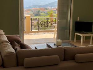 a living room with a couch and a view of a balcony at Villa Petries Relaxed Holidays in Agioi Apostoli