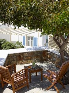 a patio with two chairs and a table under a tree at Vencia Boutique Hotel in Mýkonos City