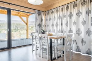 a dining room with a table and white chairs at Jagodówka in Sablówka