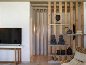 a living room with a television and shelves with vases at Vencia Boutique Hotel in Mikonos