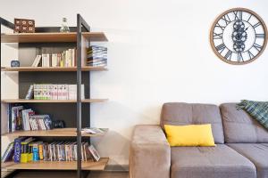 a living room with a couch and a clock on the wall at OFFRE SPECIALE Centre Verdun - Idéal Famille - Le Châtelois in Verdun-sur-Meuse