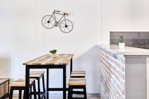 a table with chairs and a bike hanging on a wall at OFFRE SPECIALE Centre Verdun - Idéal Famille - Le Châtelois in Verdun-sur-Meuse