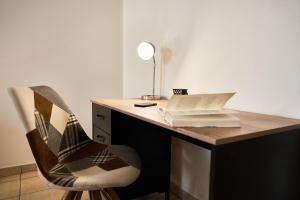 a desk with a chair with a book and a lamp at OFFRE SPECIALE Centre Verdun - Idéal Famille - Le Châtelois in Verdun-sur-Meuse