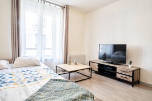 a bedroom with a bed and a flat screen tv at OFFRE SPECIALE Centre Verdun - Idéal Famille - Le Châtelois in Verdun-sur-Meuse