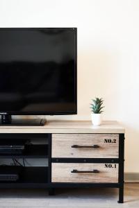 a flat screen tv sitting on top of a wooden entertainment center at OFFRE SPECIALE Centre Verdun - Idéal Famille - Le Châtelois in Verdun-sur-Meuse