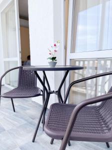 uma mesa com duas cadeiras e um vaso com flores em Blue Sky Apartments em Nesebar
