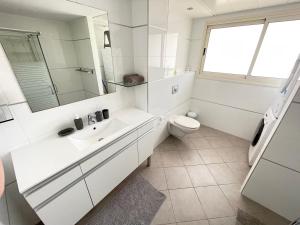 a white bathroom with a sink and a toilet at GOLF2 in Eilat