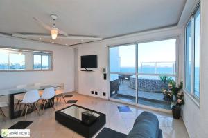 sala de estar con sofá, mesa y algunas ventanas en Incrivel cobertura de frente para o mar com 3 quartos e piscina particular em Copacabana!, en Río de Janeiro