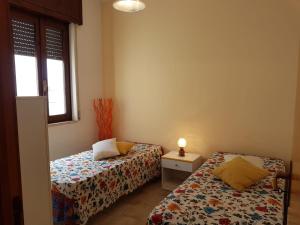 a bedroom with two beds and a table and a window at Gallipoli Mancaversa Futura Vacanza Andrea in Marina di Mancaversa