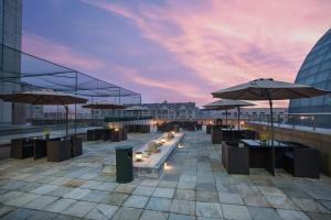 a rooftop patio with tables and umbrellas on a building at Somerset Grand Central Dalian in Dalian