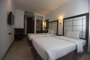 a hotel room with two beds and a television at Sukhumvit Suites Hotel in Bangkok +48 photos