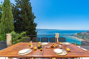 Villa Atopos with heated private pool, 5 bedrooms, Cinema room, panoramic sea views في أوميس: طاولة خشبية مع طعام فوق الشرفة