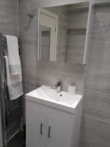 y baño con lavabo blanco y espejo. en Star London Brent Street Cosy 1-Bed Hideaway, en Hendon