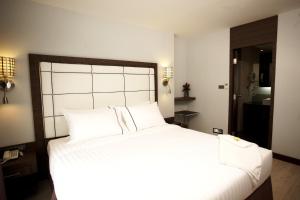 a bedroom with a large white bed with white pillows at Sukhumvit Suites Hotel in Bangkok