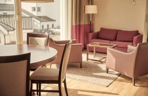 - un salon avec une table, des chaises et un canapé dans l'établissement Sola Strand Hotel, à Sola