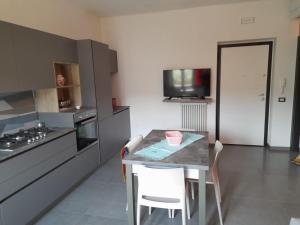 cocina con mesa con sillas y TV en Appartamenti Antico Uliveto, en Soverato Superiore