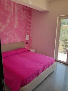 Dormitorio rosa con cama con pared de color rosa en Appartamenti Antico Uliveto, en Soverato Superiore