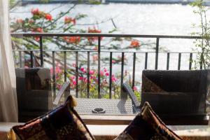 una mesa y sillas en un balcón con vistas al agua en Sala Arun en Bangkok