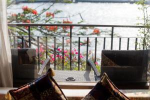 a table and chairs on a balcony with a view of the water at Sala Arun in Bangkok