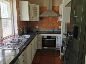 a kitchen with white cabinets and a sink and a refrigerator at 20 Montego Bay - Caribbean Estates in Port Edward