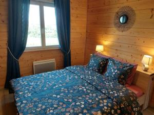 Schlafzimmer mit einem Bett mit blauer Bettwäsche und einem Fenster in der Unterkunft Entre Lacs Et Montagnes , Maison individuelle, lits préparés et ménage inclus in Barésia-sur-lʼAin