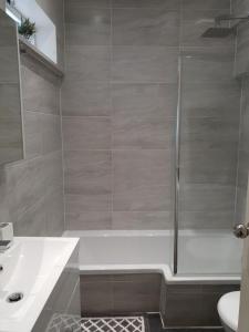 a bathroom with a shower and a tub and a sink at Star London Brent Street Cosy 1-Bed Hideaway in Hendon