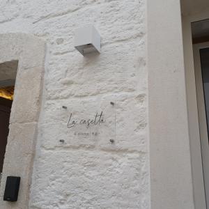 a white brick wall with a sign on it at La Casetta in Mola di Bari