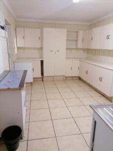 uma cozinha vazia com armários brancos e pisos em azulejo em Friends Place em Joanesburgo