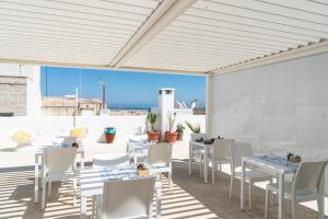 um pátio com mesas e cadeiras brancas e vista para o oceano em Donna Domenica Boutique Suites em Polignano a Mare