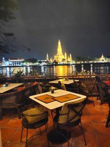 a restaurant with tables and chairs with a view of a temple at Sala Arun in Bangkok
