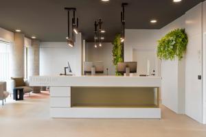 an office lobby with a white reception desk with plants at Leonardo Hotel Manchester Piccadilly in Manchester