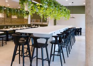 a long white bar with black stools in a restaurant at Leonardo Hotel Manchester Piccadilly in Manchester