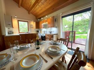 a kitchen with a table with plates and wine glasses at Pass the Keys Beautiful 3BR Lodge - Stunning Beach and Golf Location in Dalbeattie