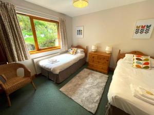 a bedroom with two beds and a chair and a window at Pass the Keys Beautiful 3BR Lodge - Stunning Beach and Golf Location in Dalbeattie