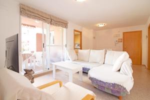 een woonkamer met een witte bank en een tafel bij Global Properties, Practico apartamento con piscina en Residencial Brezo Canet in Canet de Berenguer