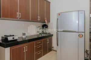 a kitchen with a white refrigerator and wooden cabinets at De Lugano SCBD Syariah Mitra RedDoorz in Jakarta