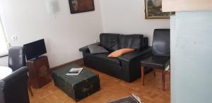 sala de estar con sofá negro y silla en Ferienhof Ziegler- Sonnenschein, en Baiersbronn