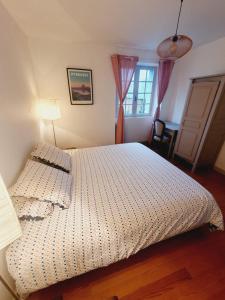 um quarto com uma cama, um candeeiro e uma janela em Gîtes Saint-Pierre em Oloron-Sainte-Marie