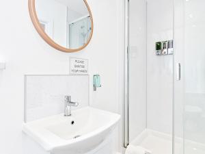 a white bathroom with a sink and a mirror at Pass the Keys Luxury Bright Spacious Family Home - Near Beaches in Swansea +14 photos