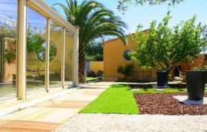 a building with a courtyard with a tree and grass at SUITE SPA PRIVATIF 66 Nord de Perpignan in Pia