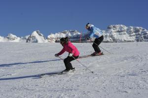 two people are skiing down a snow covered slope at Sarca Lodge Val Rendena in Dare
