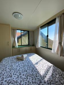 ein Schlafzimmer mit einem großen Bett und zwei Fenstern in der Unterkunft Cosy mobile house in the heart of Goricko in Moravske-Toplice