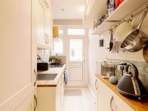 una cocina con armarios blancos y fregadero en Garden Walthamstow Apartment Pass the Keys, en Londres