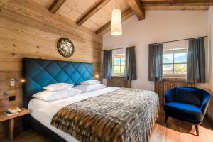 a bedroom with a large bed and a blue chair at Relais & Châteaux Gut Steinbach Hotel Chalets SPA in Reit im Winkl